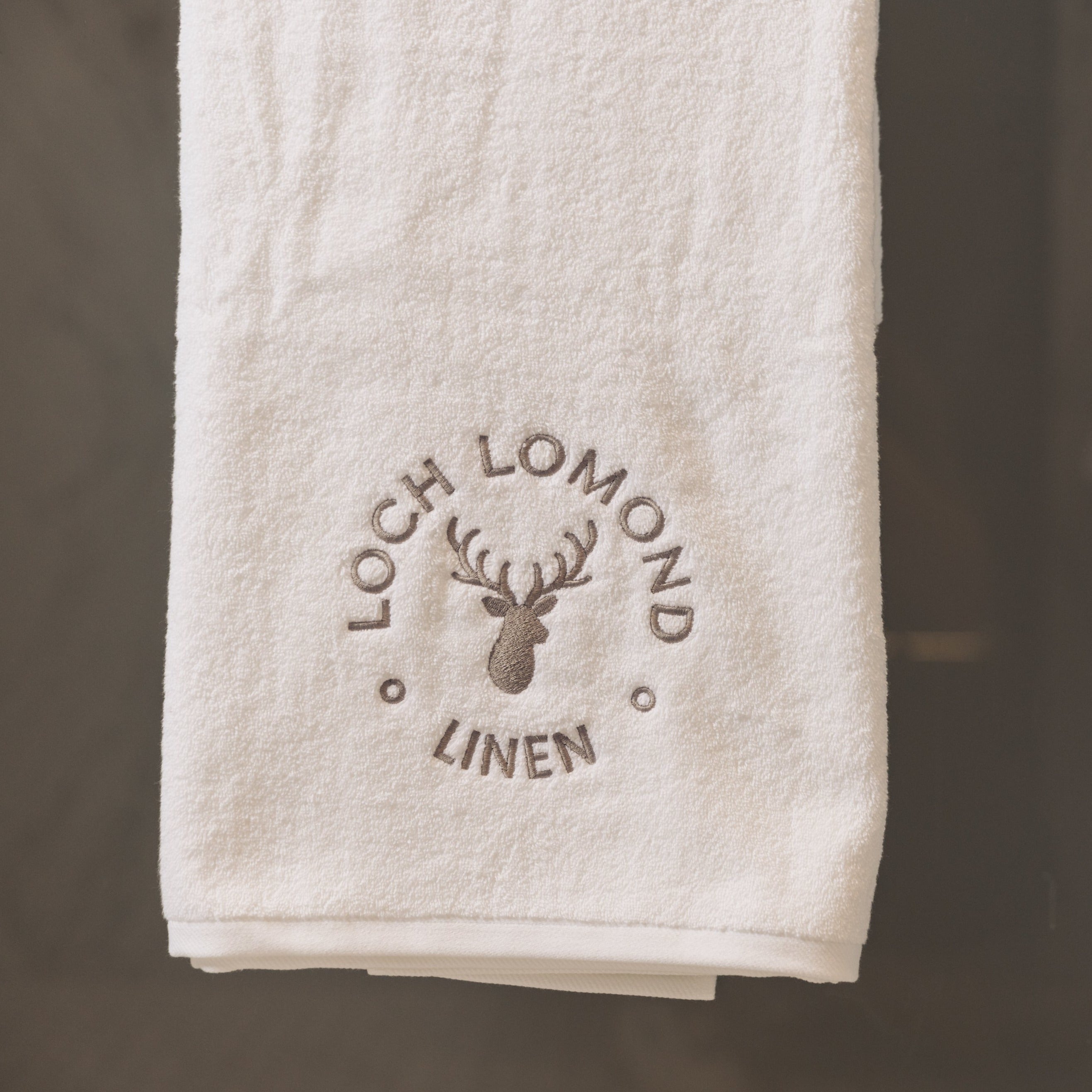 Loch Lomond Linen's luxury bath sheet is neatly folded and hung in an elegant bathroom.