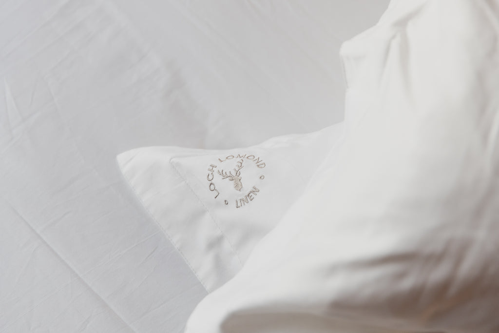 Loch Lomond Linen's grey logo is embroidered in the corner of their luxury white cotton Oxford pillowcase as well as other bedding products.