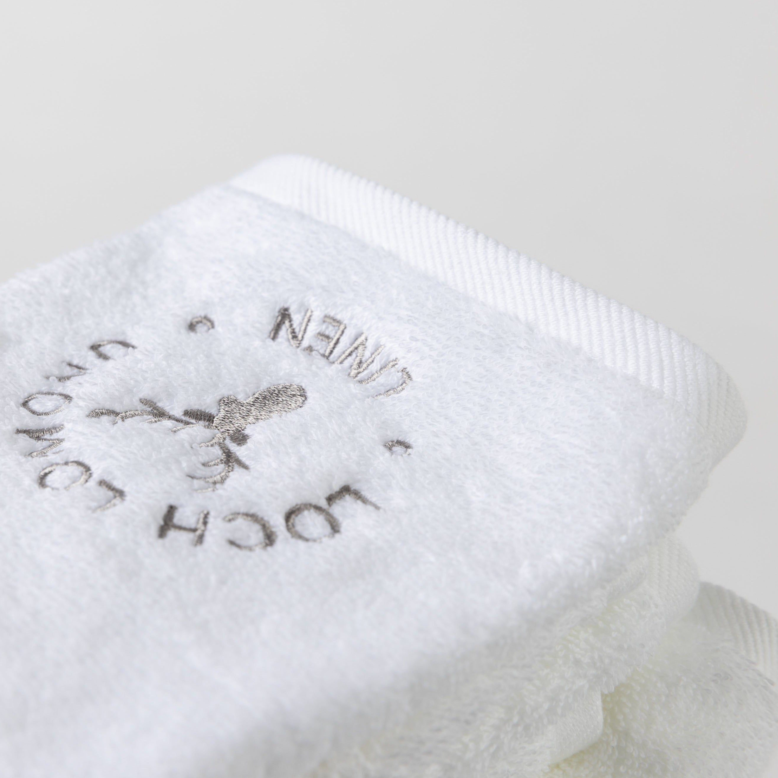 A close photo of the white face towel with the Loch Lomond Linen logo.