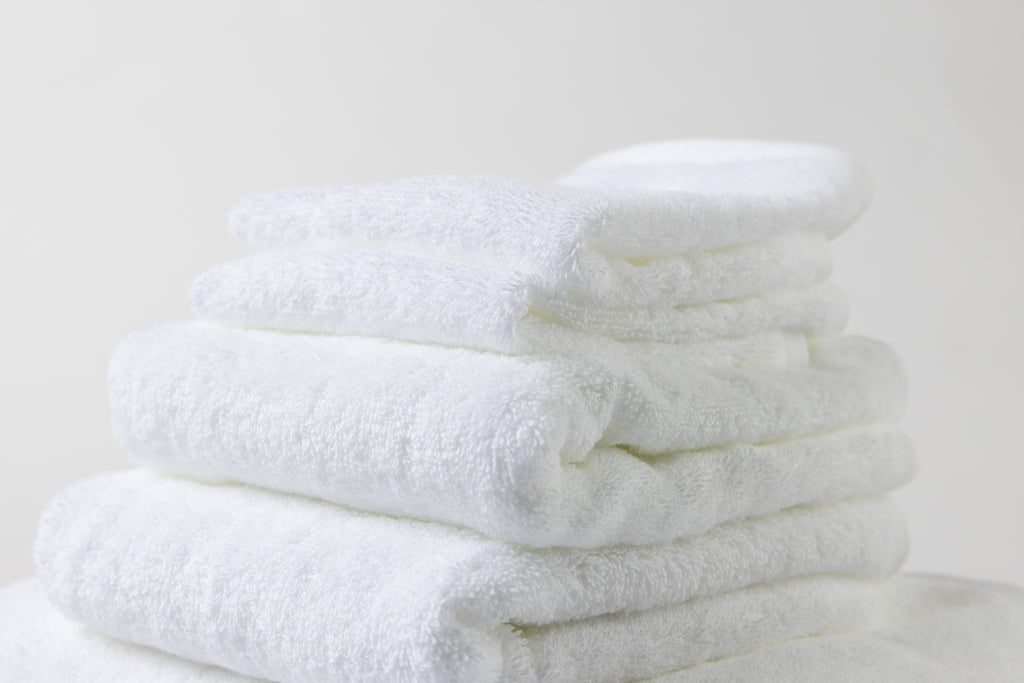 A pile of Loch Lomond Linen's luxury white cotton towels and bath sheets shown from the side.