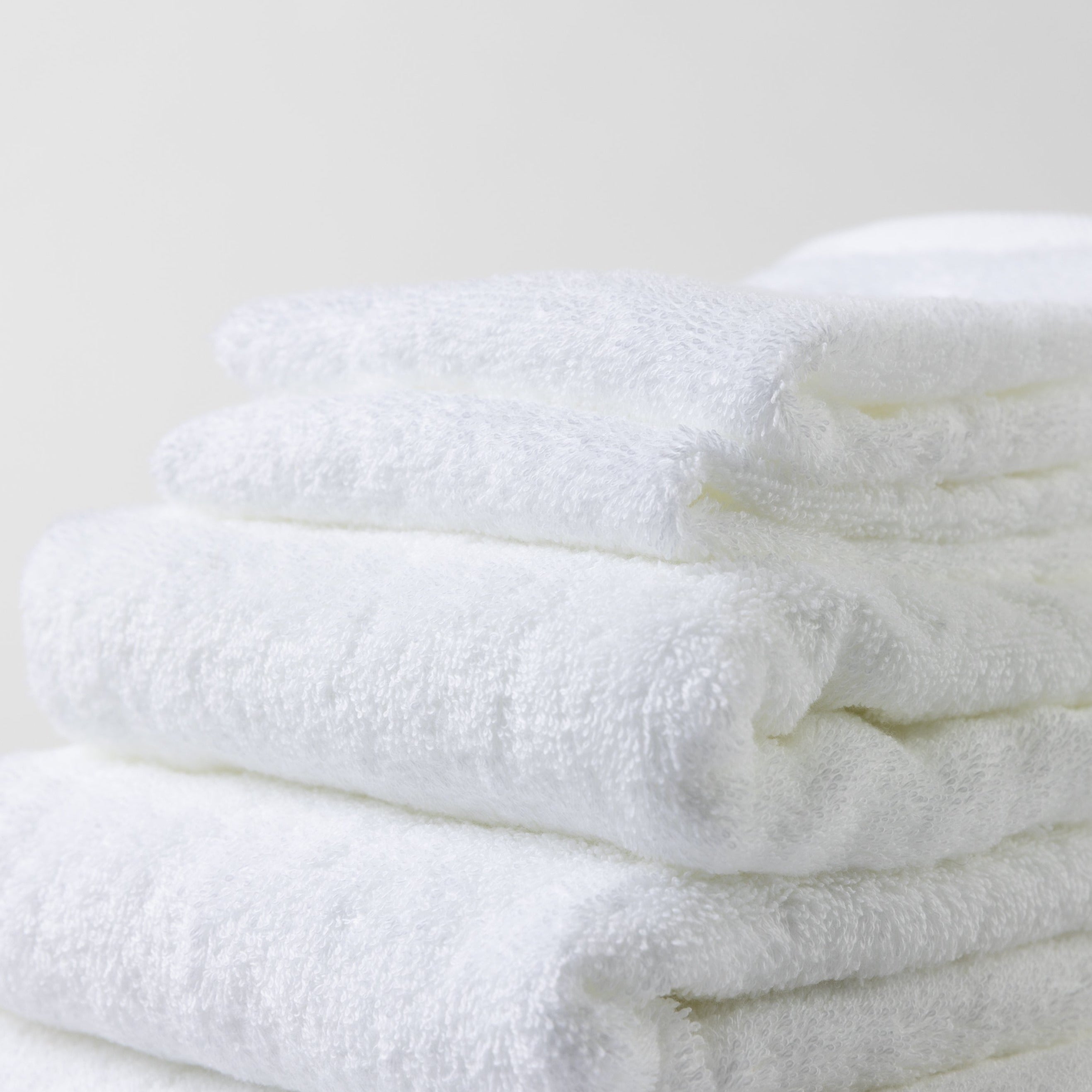 A neatly folded tower of luxurious white Loch Lomond Linen towels.