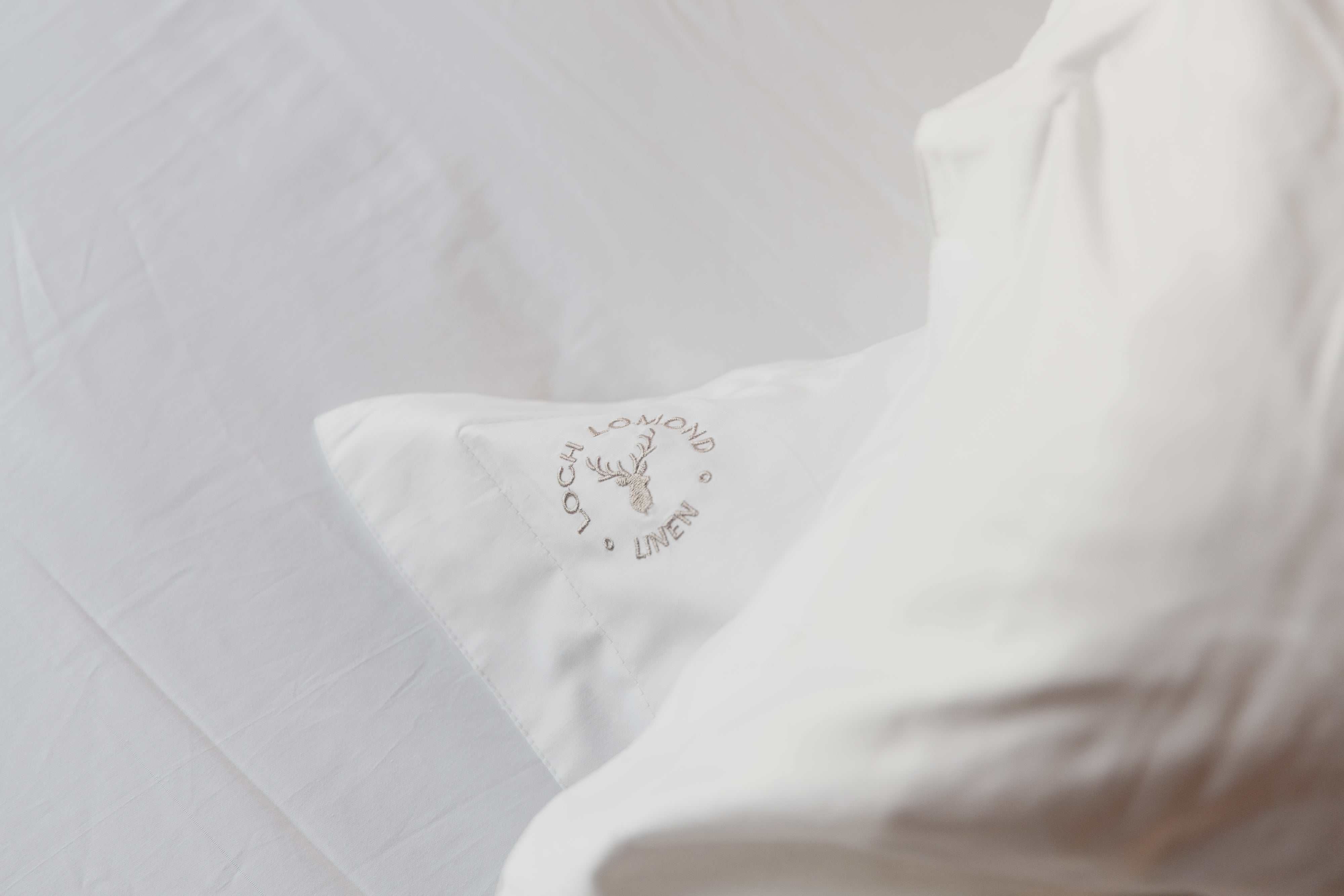 Luxury 400 thread count 100% cotton bedding from Loch Lomond shown withe the brand's logo embroidered in the corners of the products.