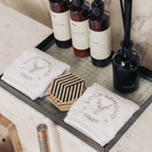 Two luxurious white 100% cotton face towels from Loch Lomond Linen is photographed in an elegant hotel bathroom with marble walls. The face towels are neatly folded into squares and placed next to some skincare products.