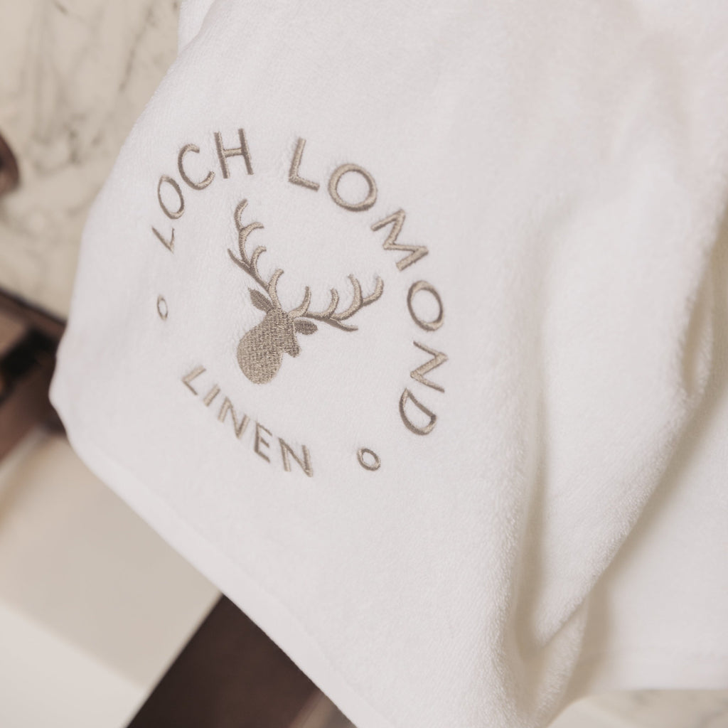 A luxurious white 100% cotton bath sheet from Loch Lomond Linen is photographed from close in a hotel room.