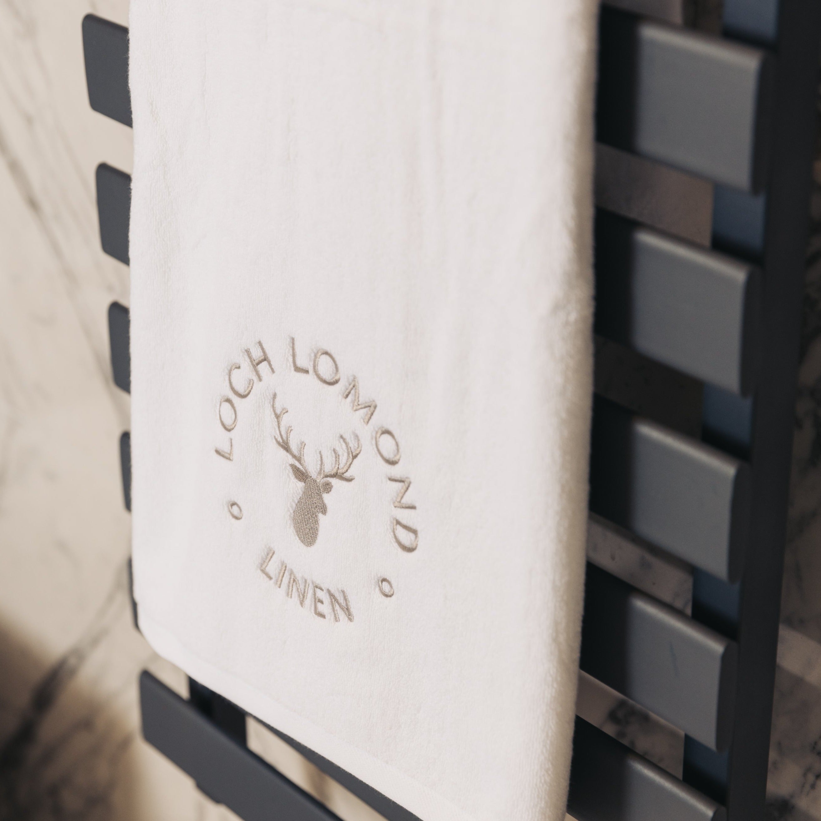 Loch Lomond Linen's luxury bath towel is neatly folded and hung in an elegant bathroom.