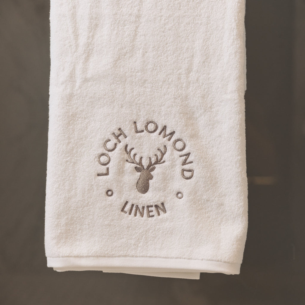 Loch Lomond Linen's luxury bath sheet is neatly folded and hung in an elegant bathroom. 