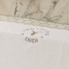 A close photo of Loch Lomond Linen's elegant grey logo embroidered on the white cotton mat.