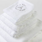 One bath sheet, two bath towels, two hand towels and two face towels are folded into a tower and photographed from the top. The grey Loch Lomond Linen logo is elegantly embroidered on the products.