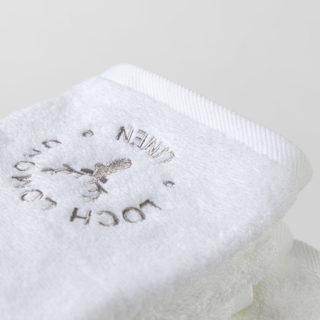 A close photo of the white face towel with the Loch Lomond Linen logo.