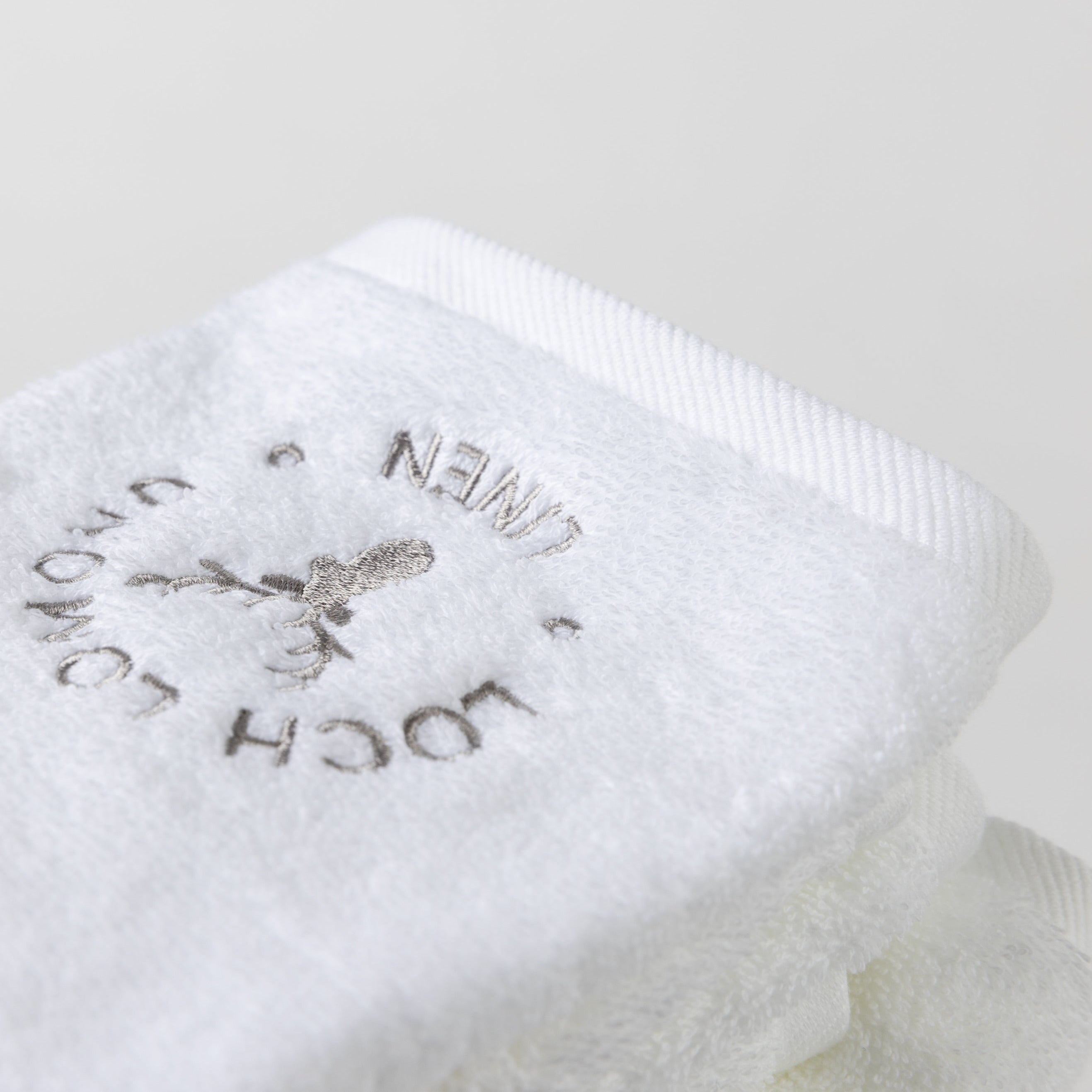 A close photo of the white face towel with the Loch Lomond Linen logo.