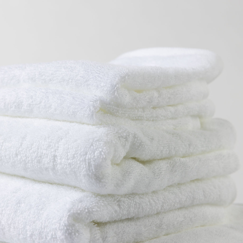 A neatly folded tower of luxurious white Loch Lomond Linen towels.