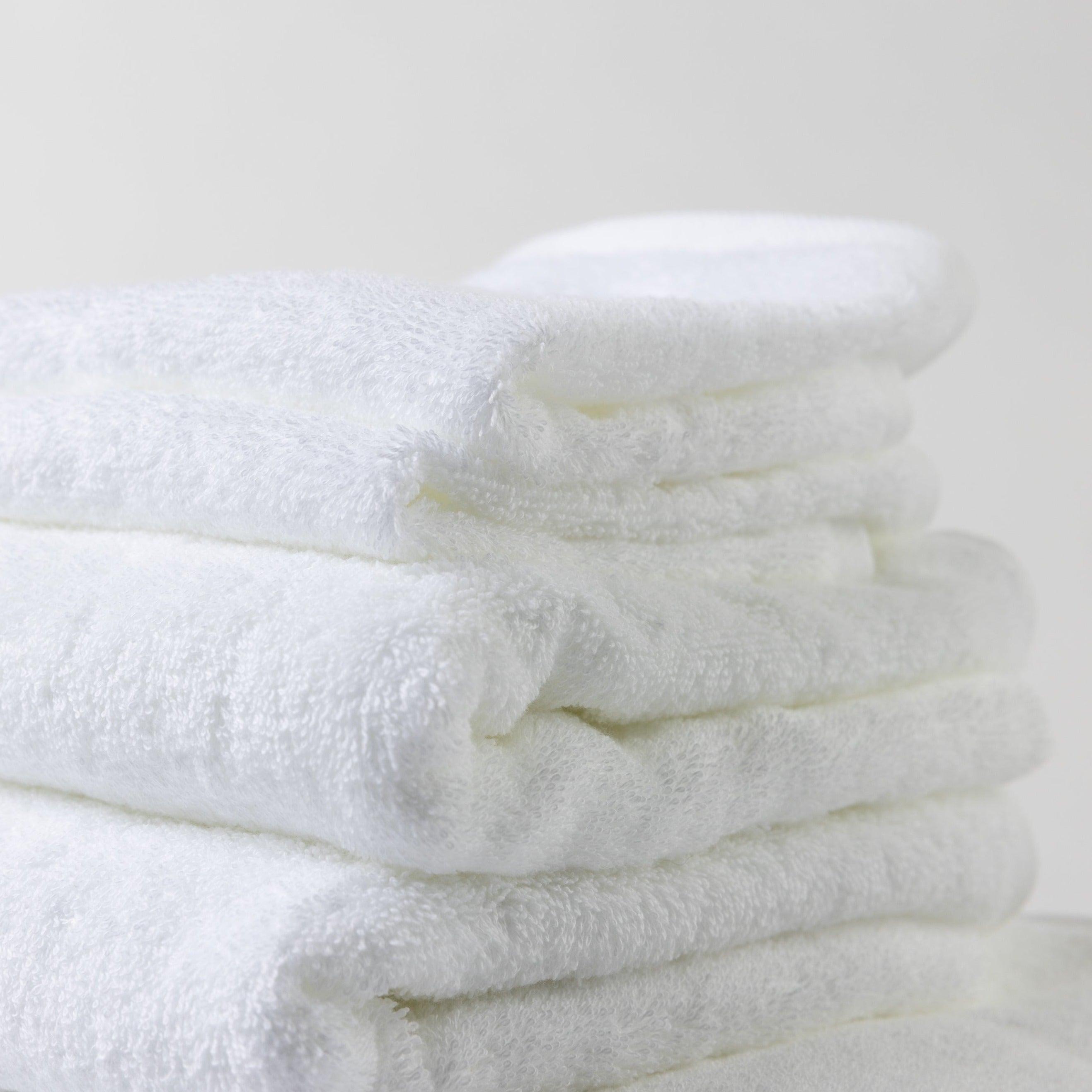 A neatly folded tower of luxurious white Loch Lomond Linen towels.