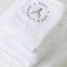 A set of six luxury 100% cotton white towels are shown withe elegant grey Loch Lomond Linen logo embroidered on the top product.