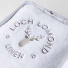 Close photo of the grey Loch Lomond Linen logo embroidered on a white 100% cotton towel.