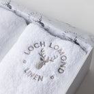Close up photo of the towel box set showing the embroidered Loch Lomond Linen logo on top of the white cotton towel.