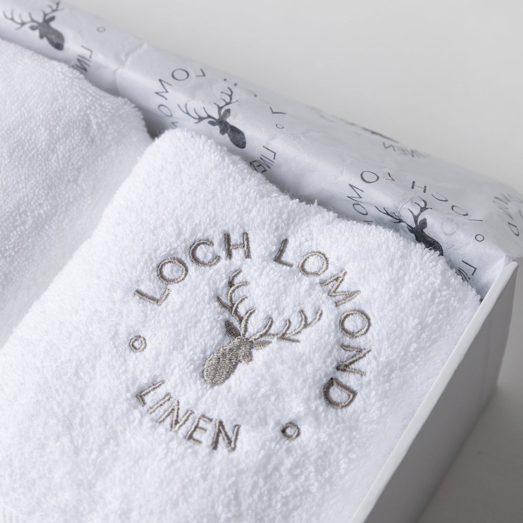 Close up photo of the towel box set showing the embroidered Loch Lomond Linen logo on top of the white cotton towel.