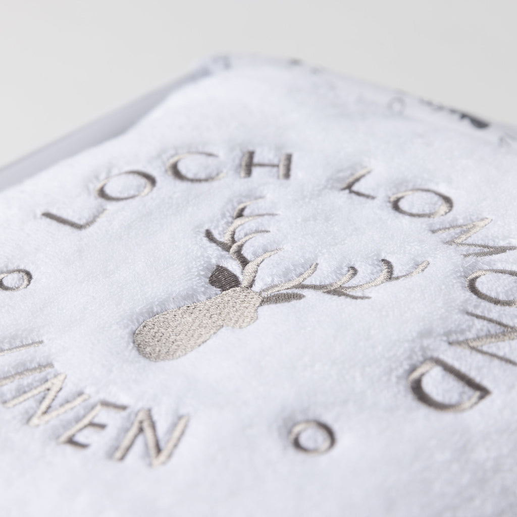 Close macro shot of the Loch Lomond Linen logo embroidered onto the white cotton towel.