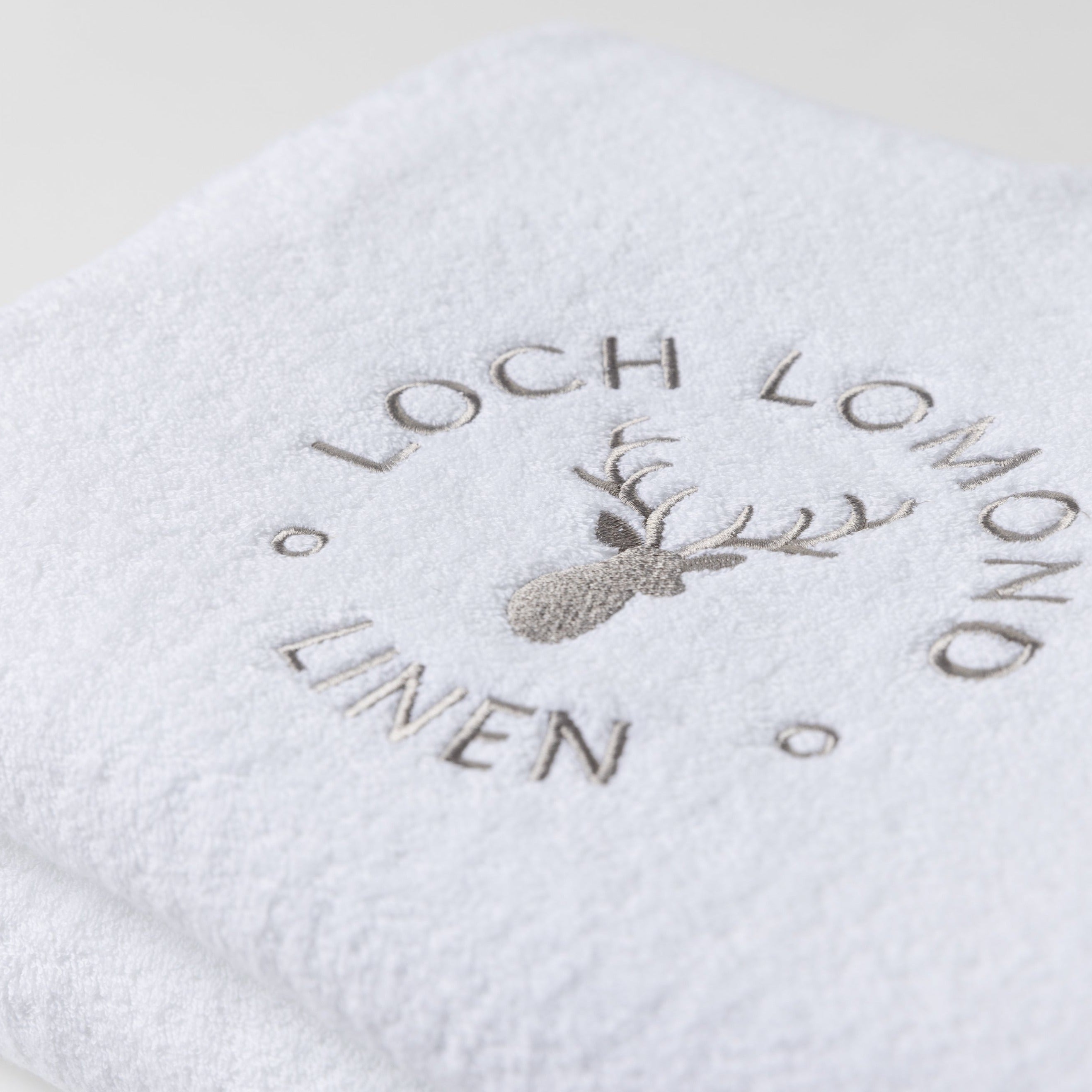Close photo of the Loch Lomond Linen logo that is embroidered onto the white cotton towels.