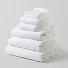 Loch Lomond Linen's seven piece bath sheet and towel set is shown neatly folded on top of each other. All the towels are white and made of the finest 100% cotton.