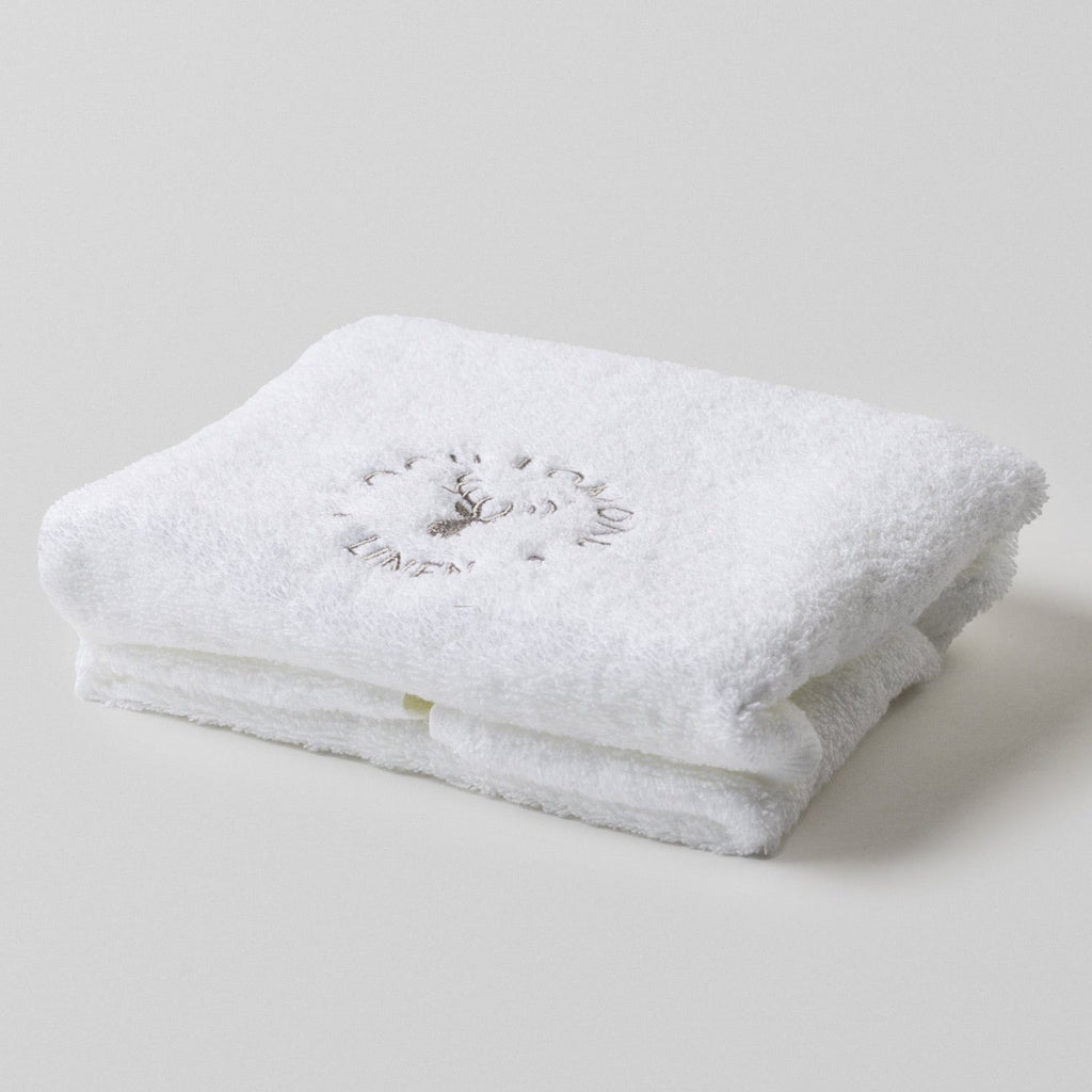 Loch Lomond Linen's white 100% cotton luxury hand towel is photographed on it own. The hand towel is neatly folded with the elegant grey logo showing on the top.