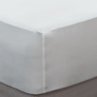 Loch Lomond Linen's white fitted bed sheet is shown on a mattress. Thanks to its elastic corners, the sheet cradles the mattress like a glove.