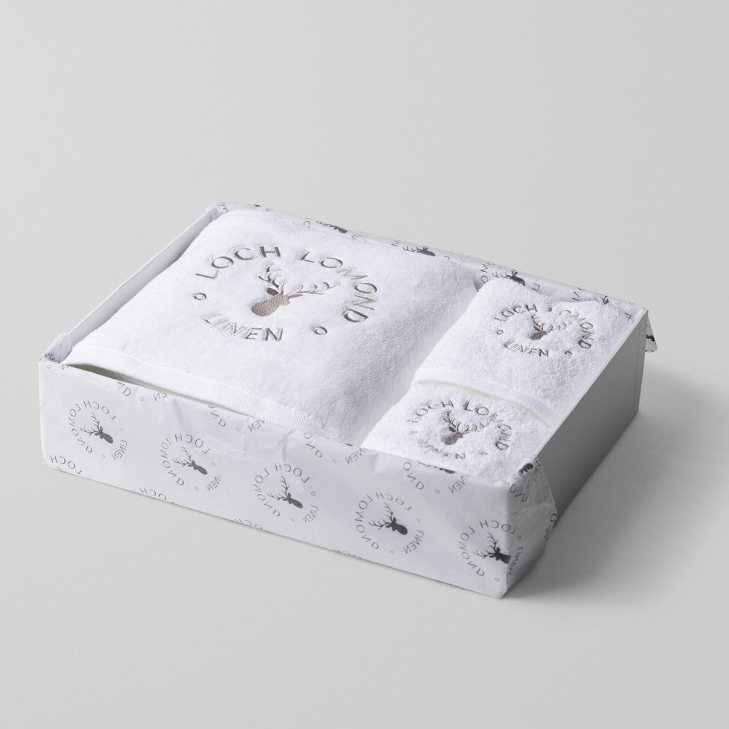 A box of three white towels including one bath towel, one hand towel and one face towel. They are neatly folded in a box that is branded with Loch Lomon Linen's logo.