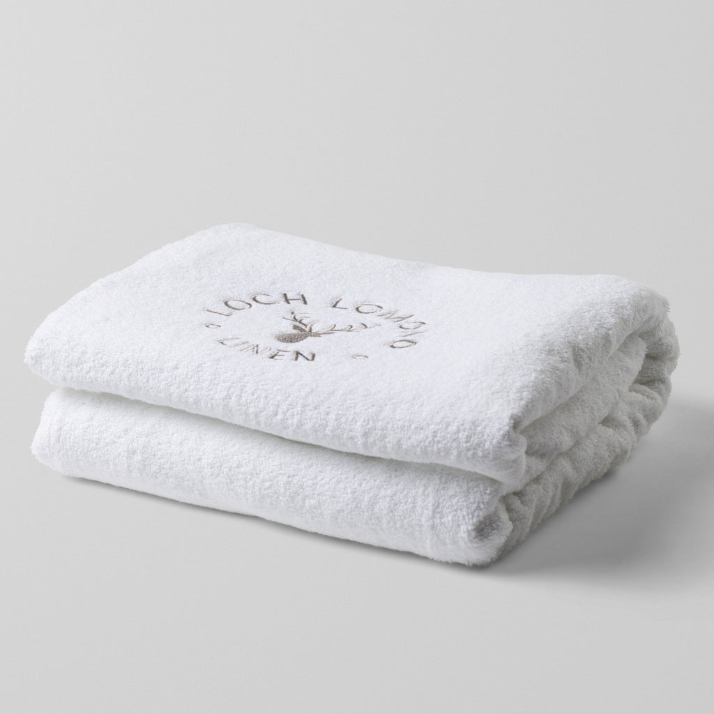 Loch Lomond Linen's white 100% cotton luxury bath sheet is photographed on it own. The bath sheet is neatly folded with the elegant grey logo showing on the top.