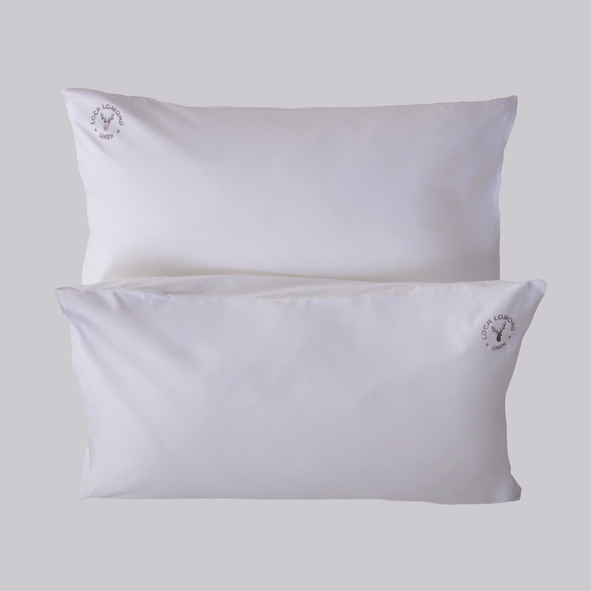 A pair of luxurious Housewife (envelope) pillowcases are shown with Loch Lomond Linen's logo embroidered in the corners. Made of 100% cotton sateen to ensure the best night's sleep.