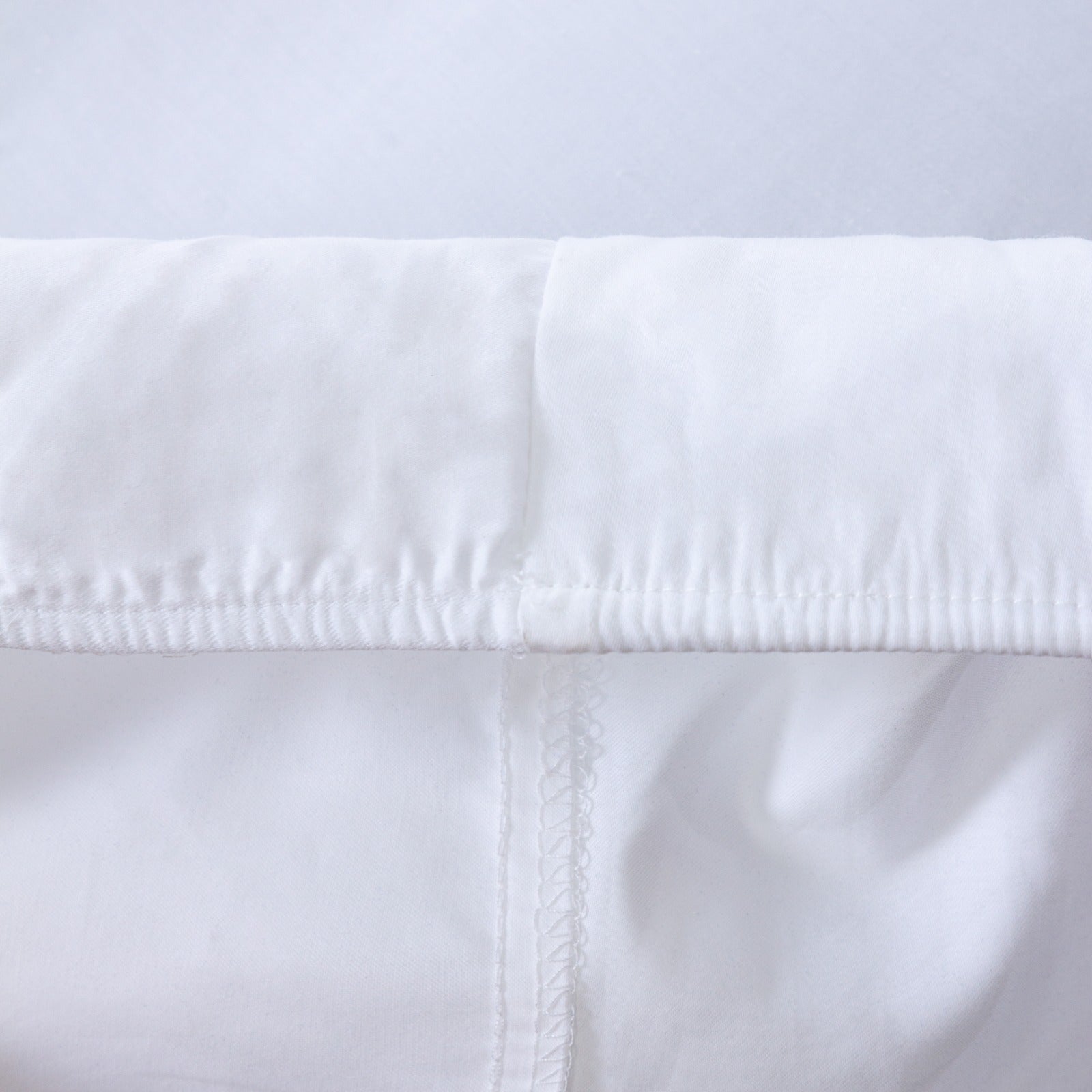Loch Lomond Linen's white fitted bed sheet's elastic corners are shown in detail. They ensure a snug, tailored fit.
