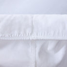 Loch Lomond Linen's white fitted bed sheet's elastic corners are shown in detail. They ensure a snug, tailored fit.